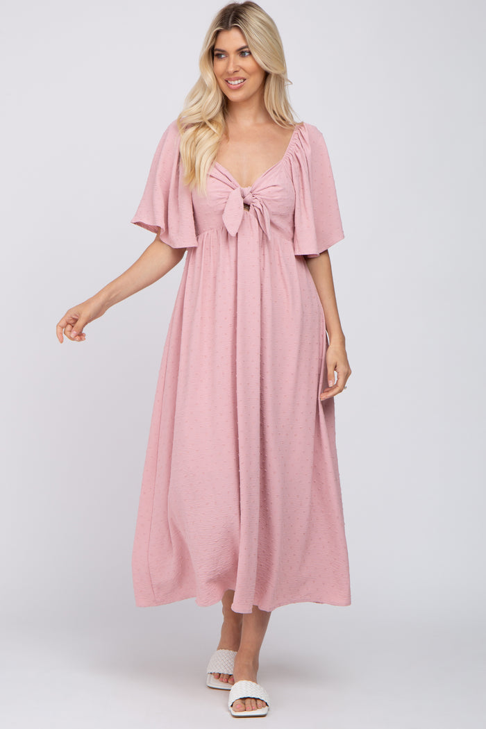 woman wearing a light pink maxi dress with flutter sleeves and a tie-front detail