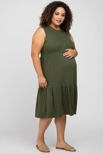 Pregnant woman with curly hair wearing an olive green sleeveless ribbed maternity dress and tan sandals