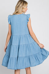 woman wearing a light blue tiered denim dress with ruffled sleeves, twirling to show the back view