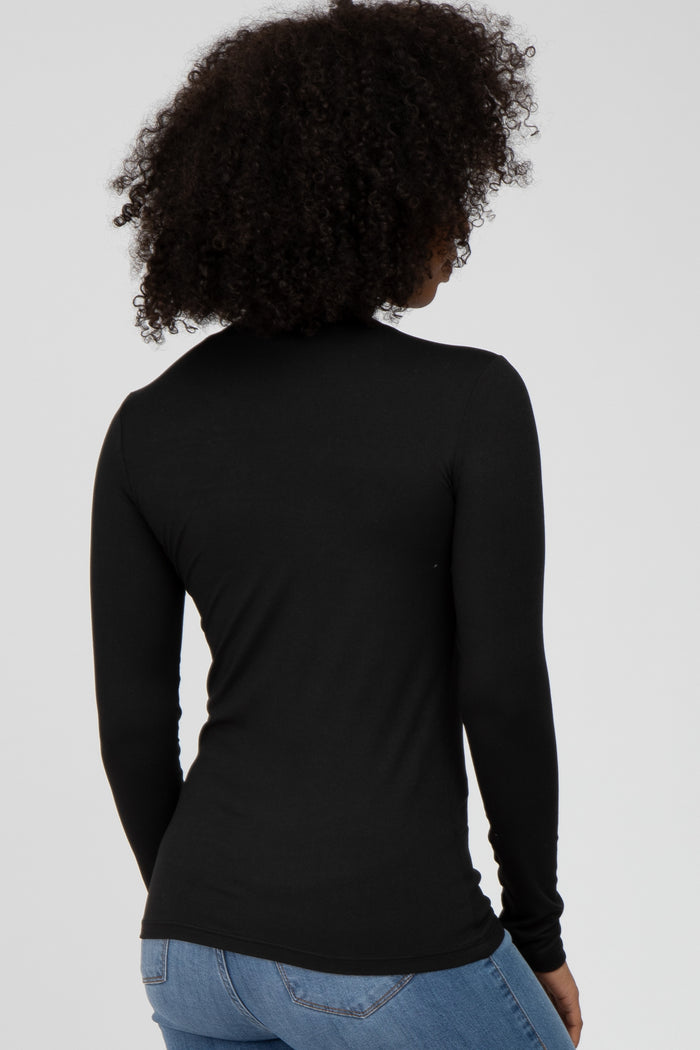 woman wearing a fitted black long sleeve top, viewed from the back, paired with light blue jeans