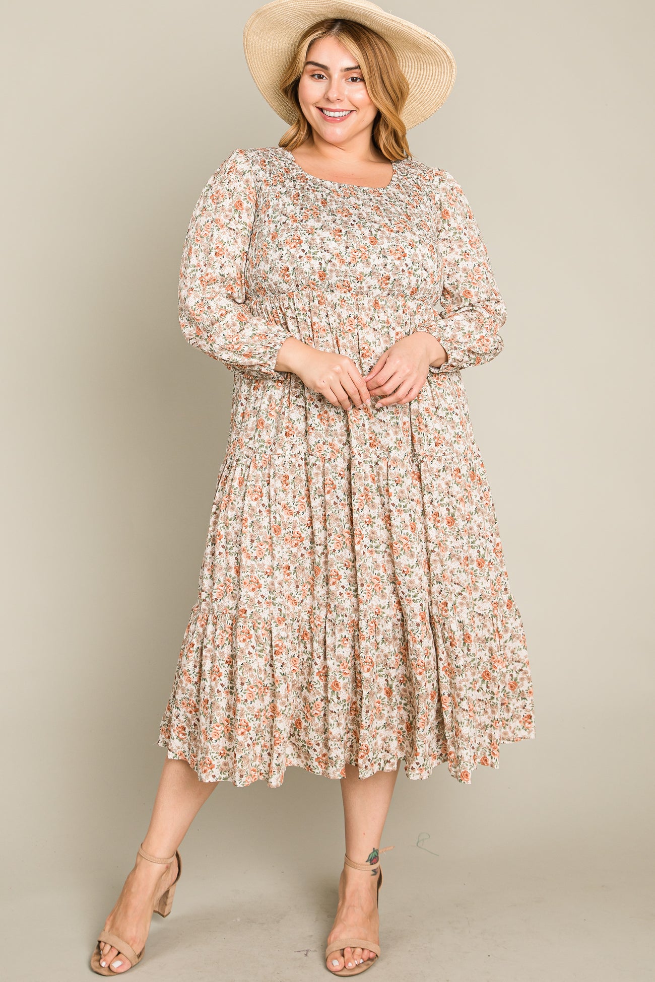 woman wearing a floral print midi dress with long sleeves and a tiered skirt, paired with a wide-brimmed hat and sandals