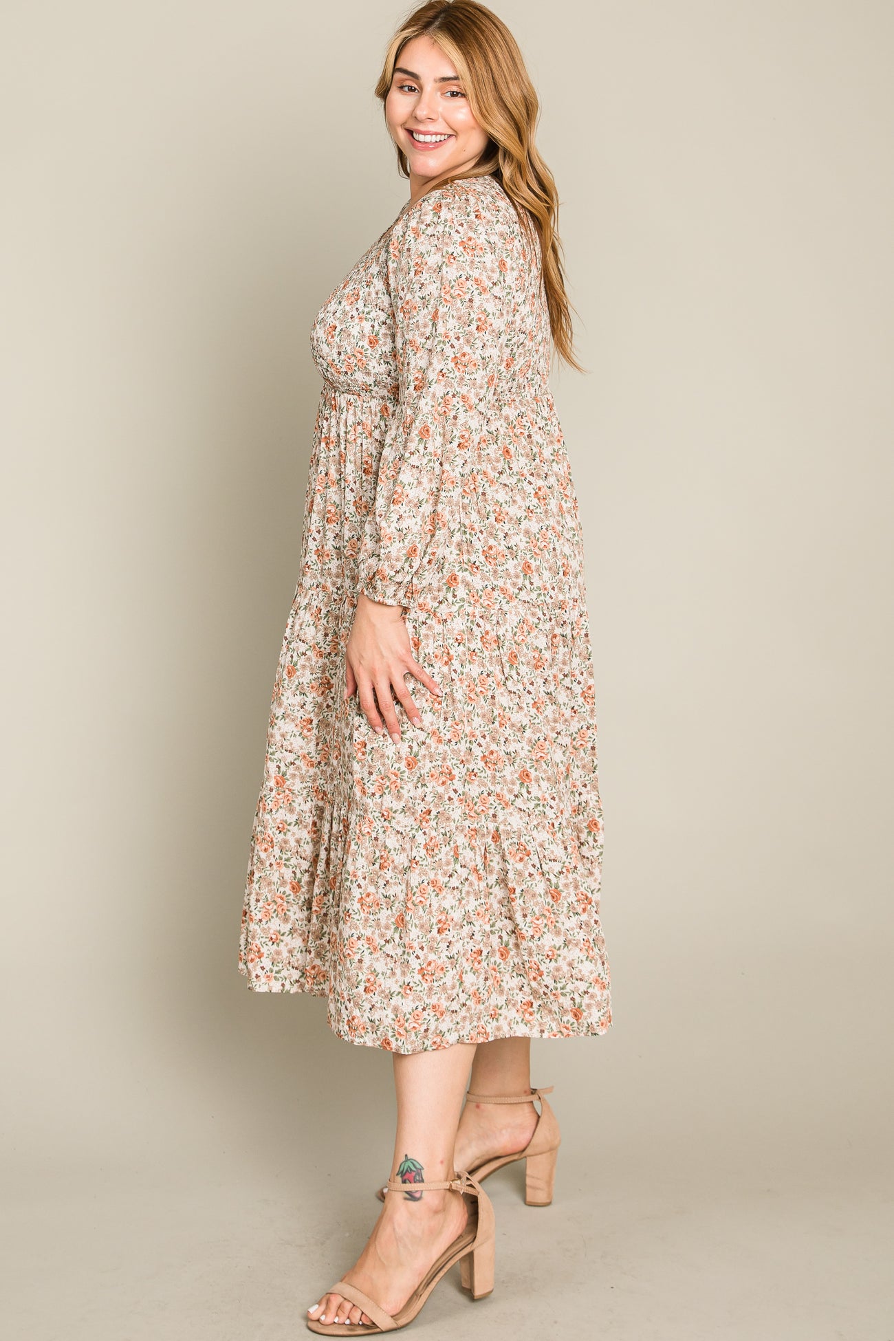 woman wearing a floral print plus size maxi dress with long sleeves and smocked waist, standing sideways
