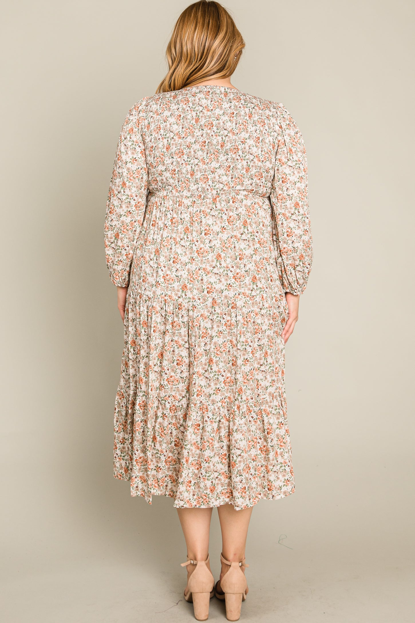 woman wearing a floral patterned plus-size midi dress with long sleeves and a tiered skirt, view from the back