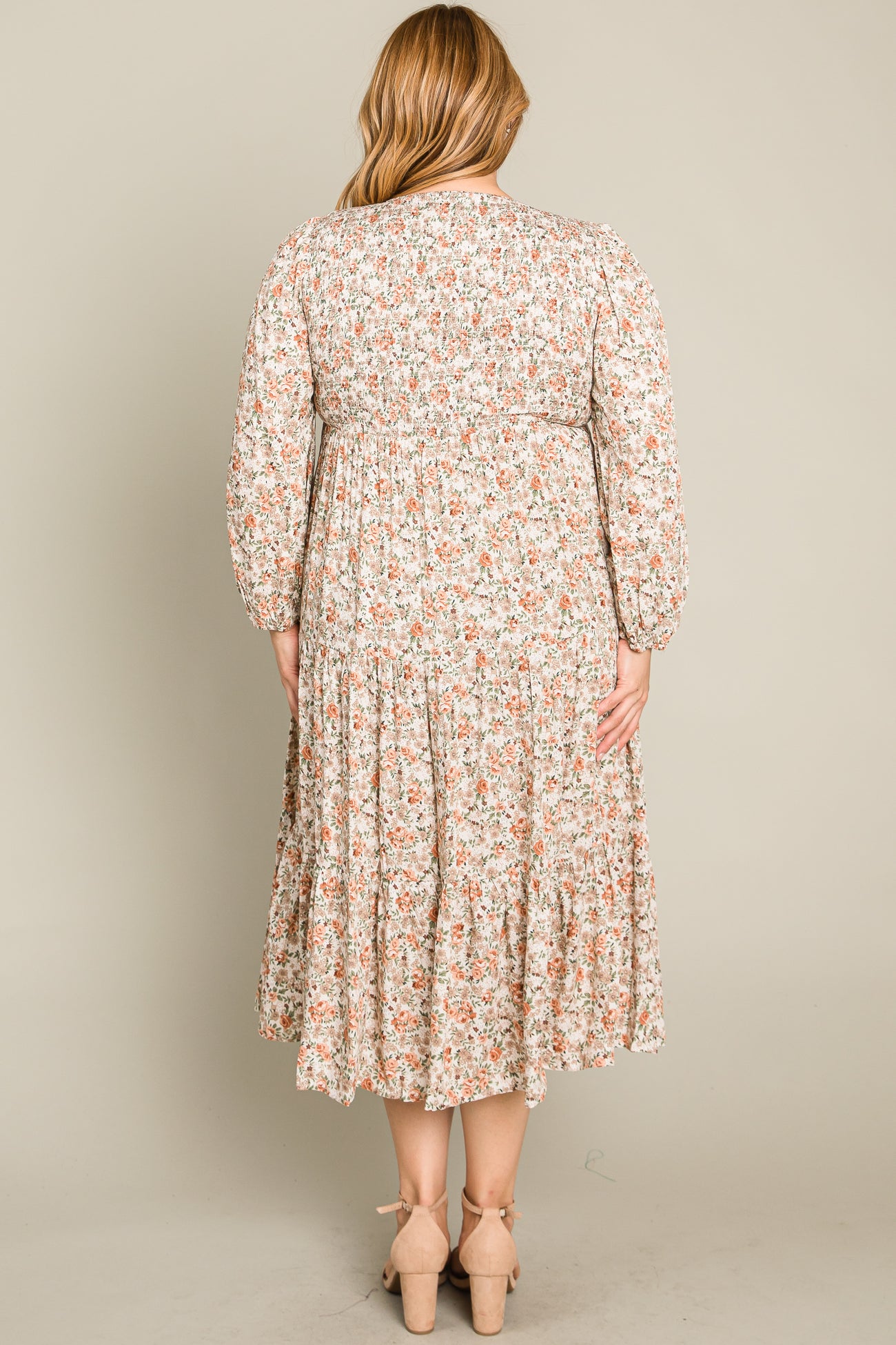 woman wearing a floral print plus size midi dress with long sleeves and a tiered skirt, seen from the back