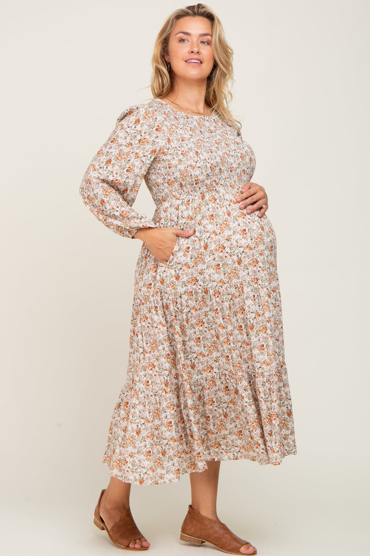 woman wearing a floral long sleeve maternity dress with pockets and showing her baby bump