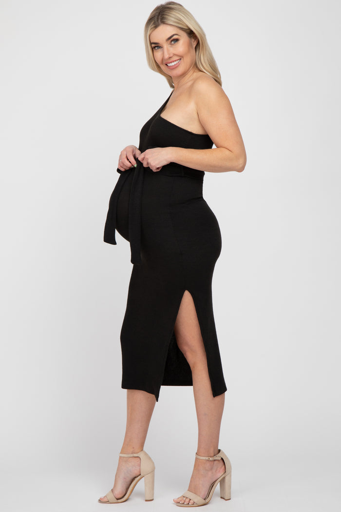 woman wearing a black ribbed maternity dress with a side slit and tie detail, showcasing her baby bump