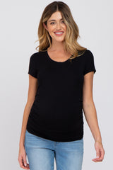 woman wearing a black short sleeve maternity top with side ruching and visible baby bump