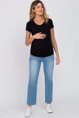 Pregnant woman wearing a black short sleeve maternity top and light wash blue jeans with white sneakers