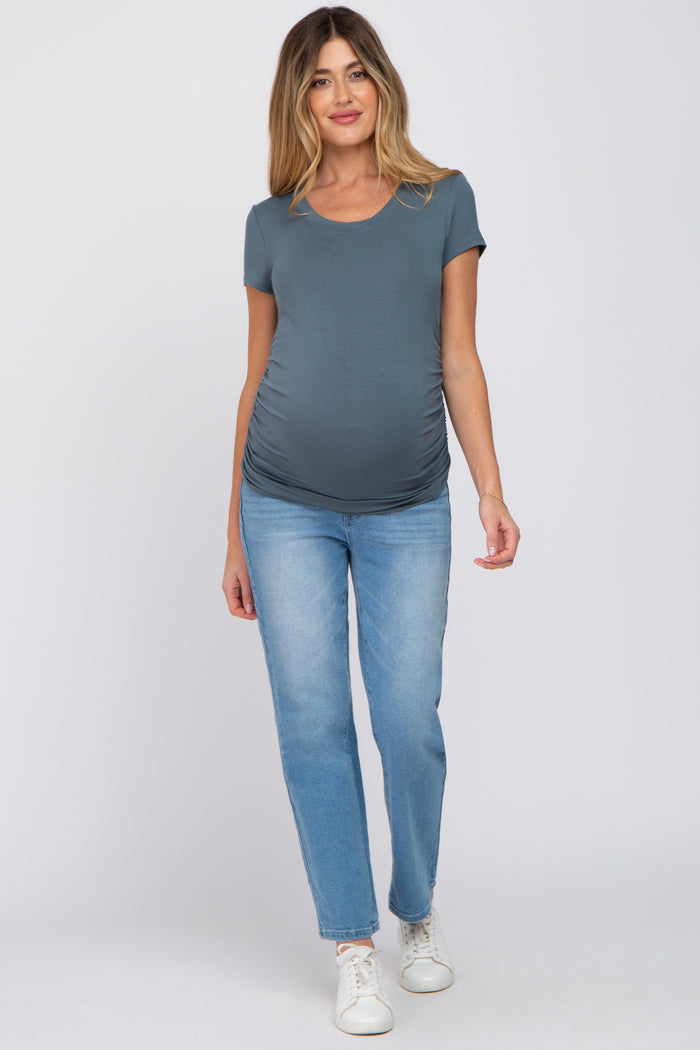 woman wearing a gray short sleeve maternity top and blue jeans, showing her baby bump