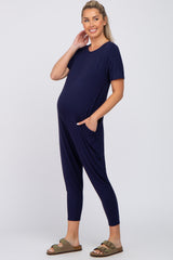 woman wearing a navy blue short sleeve maternity jumpsuit with side pockets and a visible baby bump