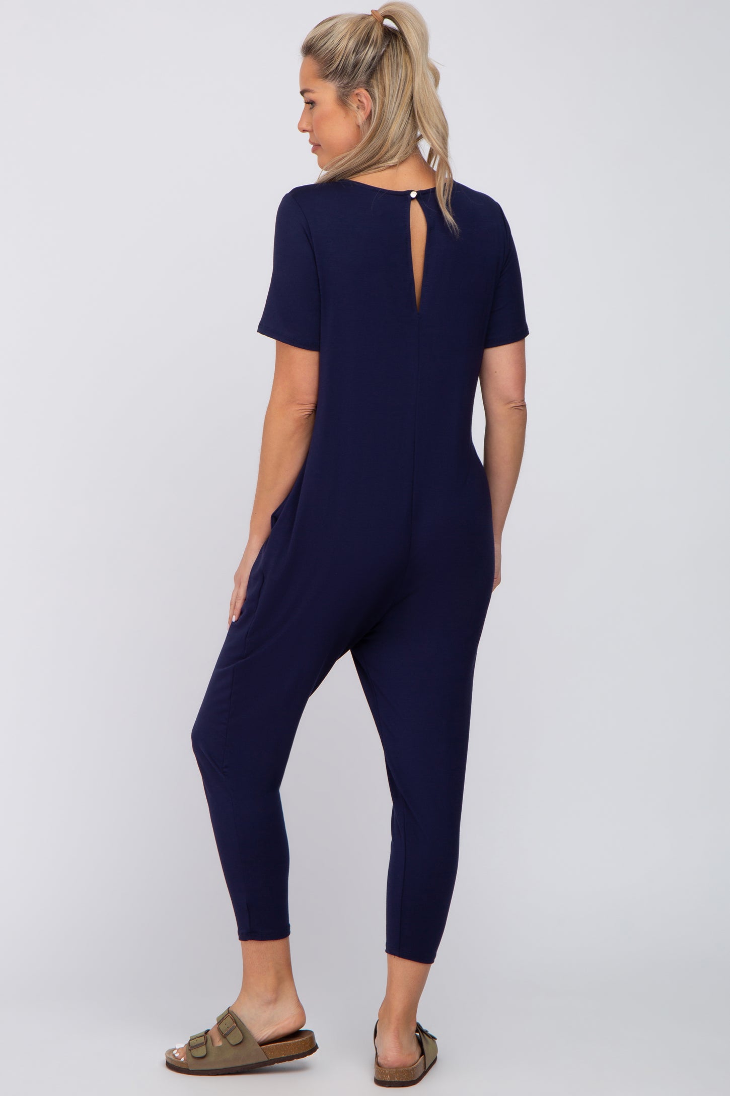 woman wearing a navy blue maternity jumpsuit with short sleeves and a keyhole back detail