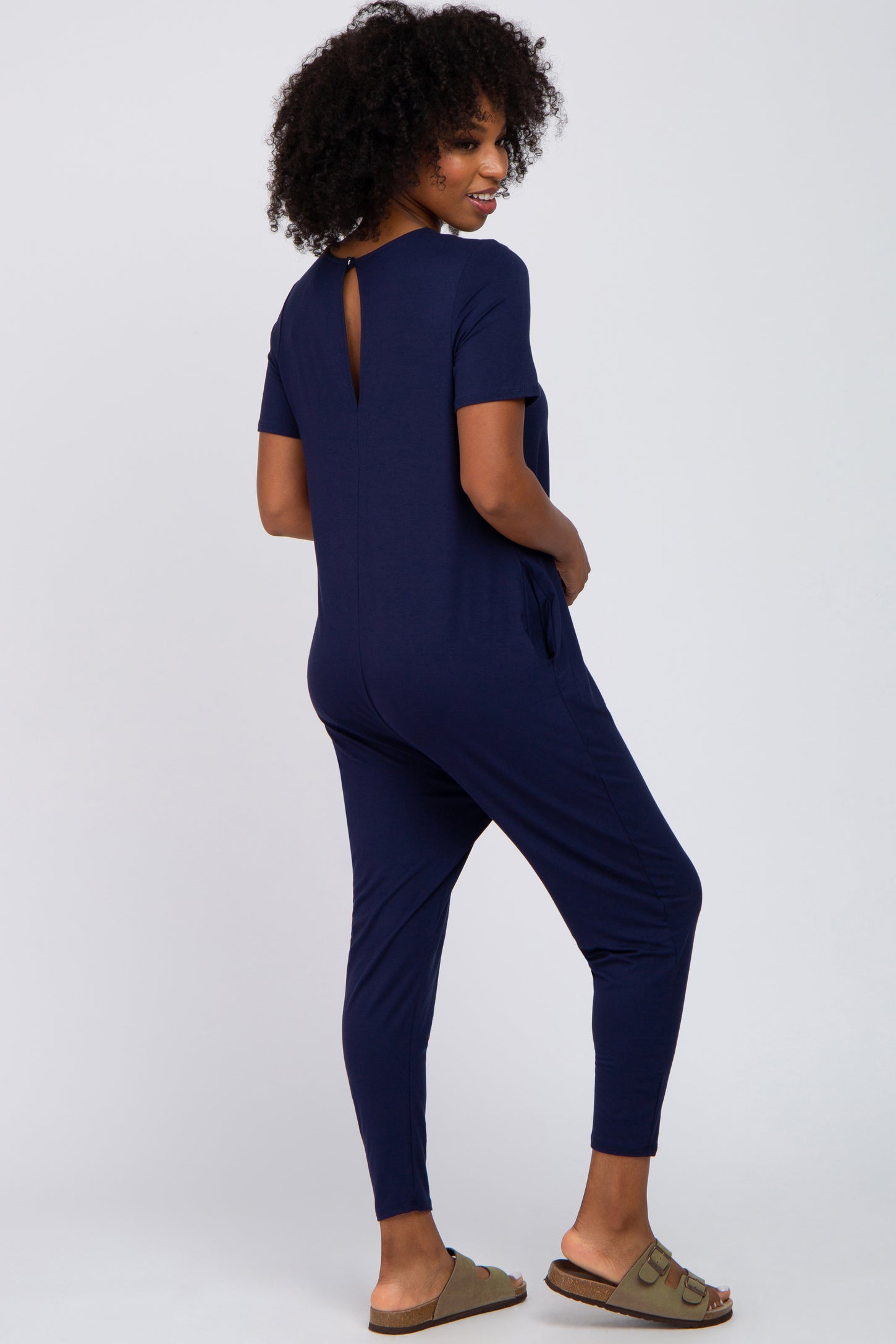 woman wearing a navy blue short sleeve jumpsuit with a back keyhole detail and side pockets