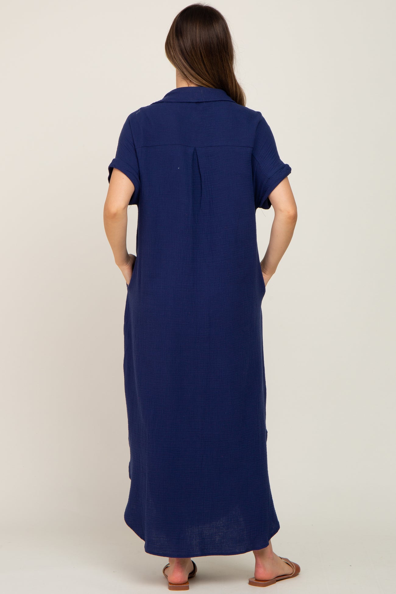 woman wearing a navy blue short sleeve maternity dress with a collar and back pleat, shown from the back