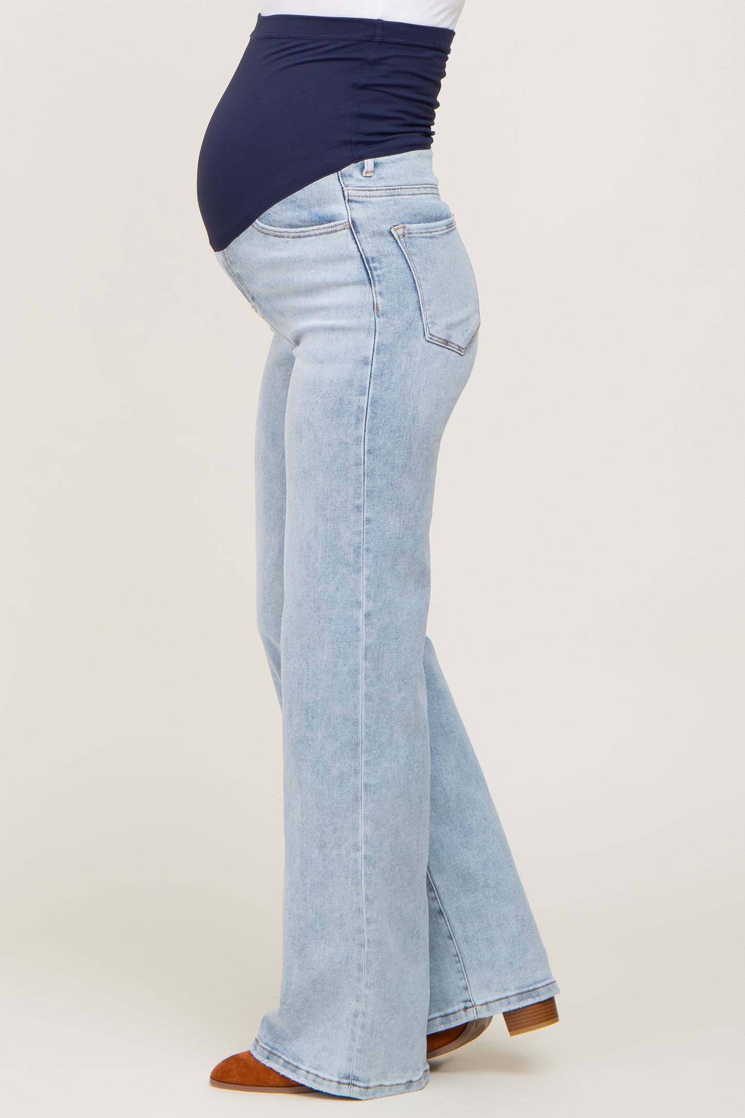 woman wearing light blue maternity flared jeans and a navy top, showing her baby bump