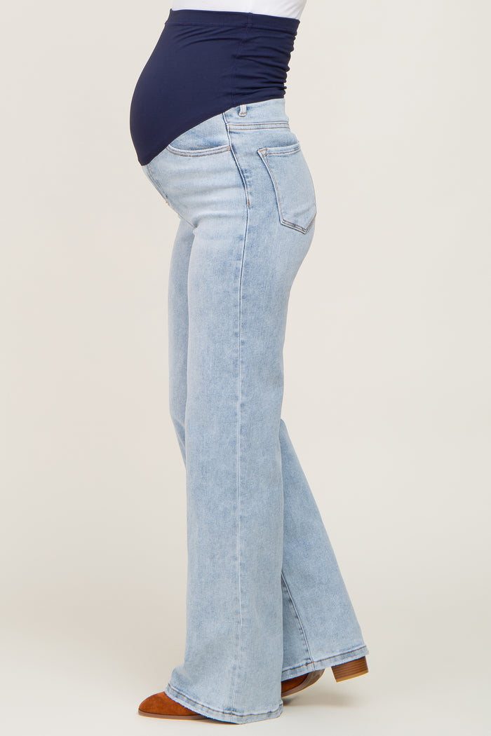 woman wearing light blue maternity flared jeans and a navy top, showing her baby bump