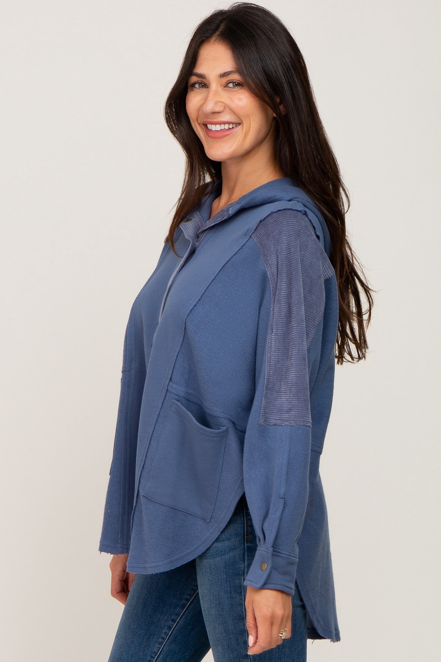 woman wearing a navy blue oversized hoodie with a front pocket and long sleeves, smiling at the camera
