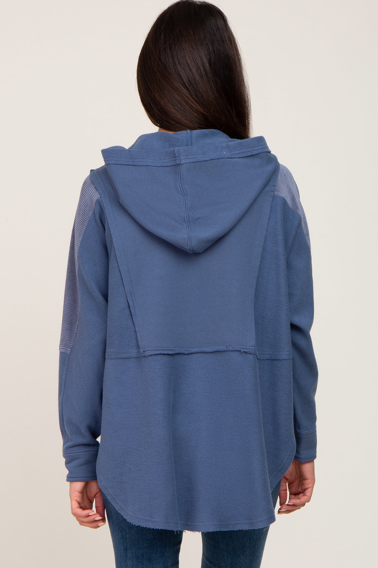woman wearing a navy blue hooded oversized top with a relaxed fit and contrast stitching details