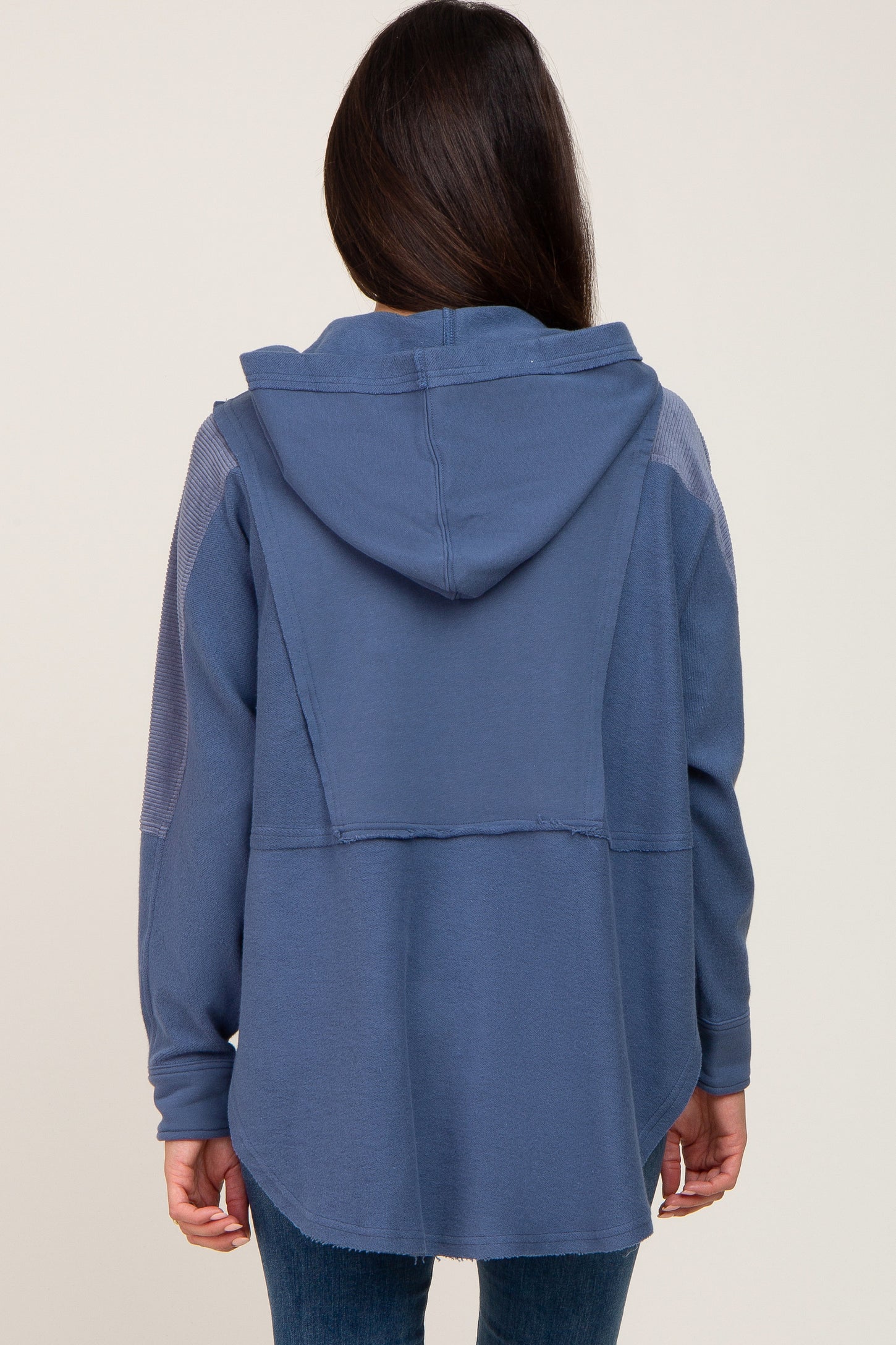 woman wearing a navy blue hooded oversized top with a relaxed fit and contrast stitching details