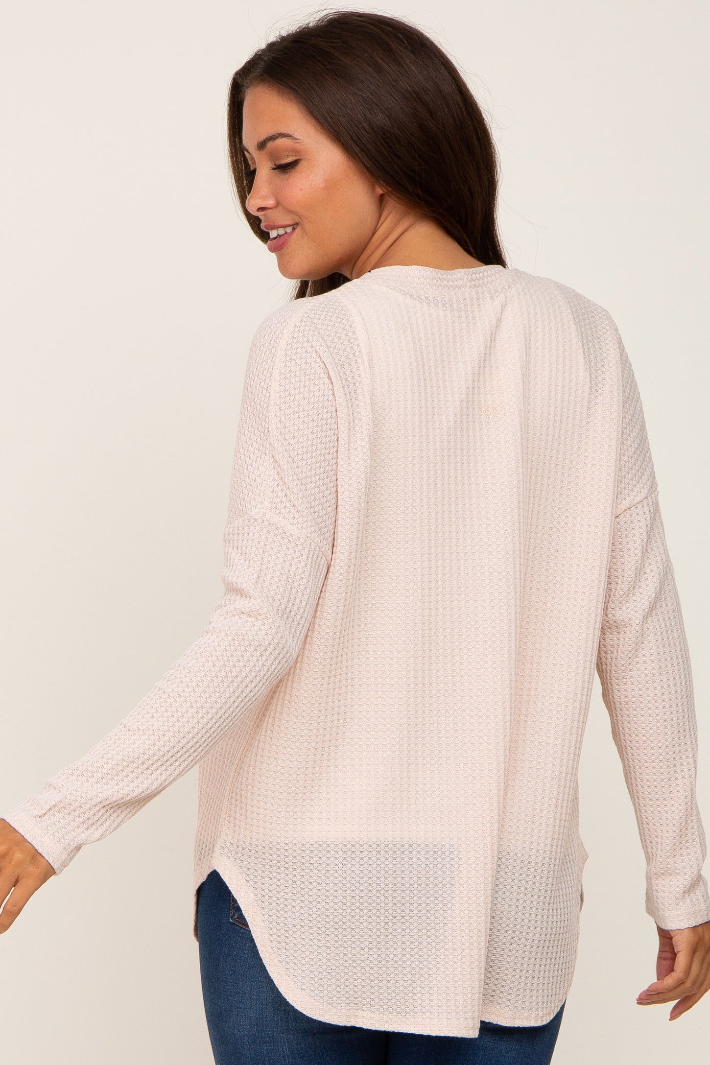 woman wearing a light pink maternity long sleeve top with a textured finish and a relaxed fit