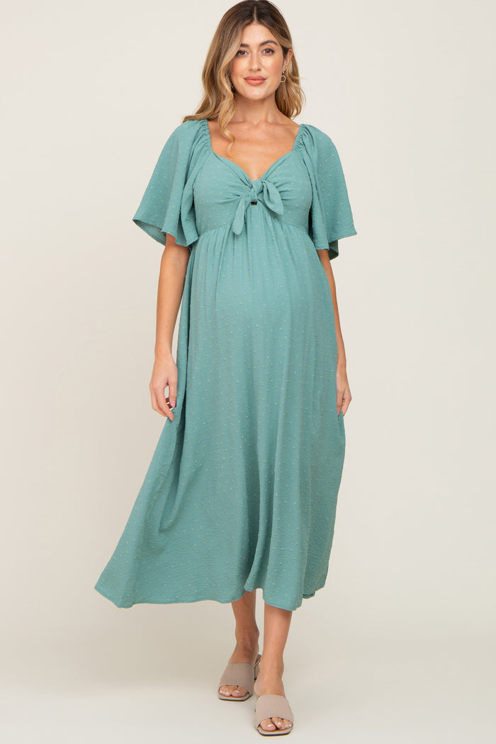 woman wearing a teal maternity maxi dress with a tie front and flutter sleeves, showing her baby bump