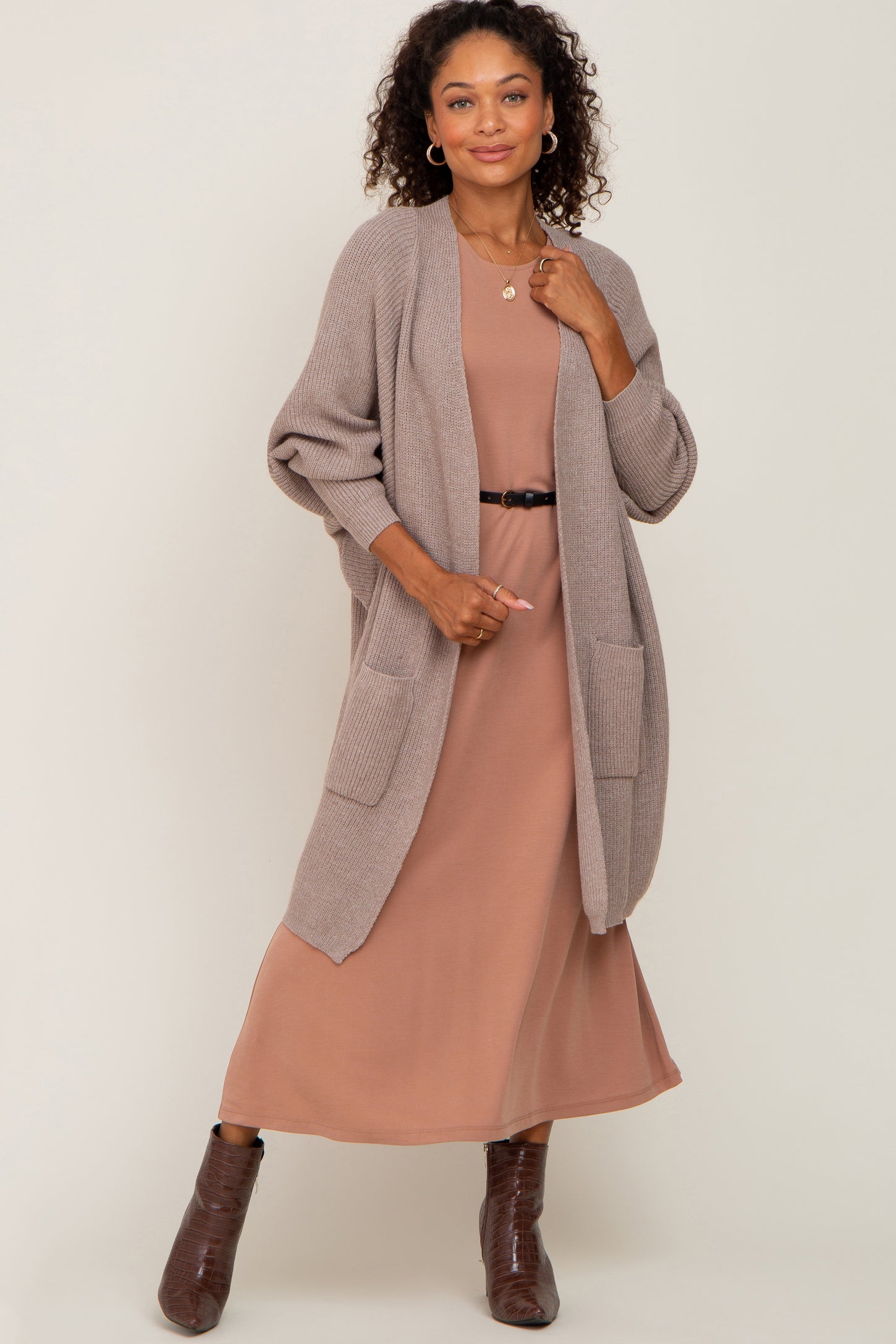 woman wearing a beige long cardigan over a brown maxi dress with pockets and chunky boots