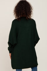 woman wearing a dark green oversized knit sweater with a relaxed fit and batwing sleeves