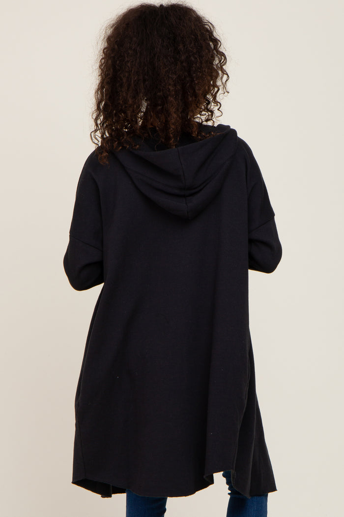woman wearing a black long hooded cardigan, viewed from the back, with a relaxed fit and curved hem
