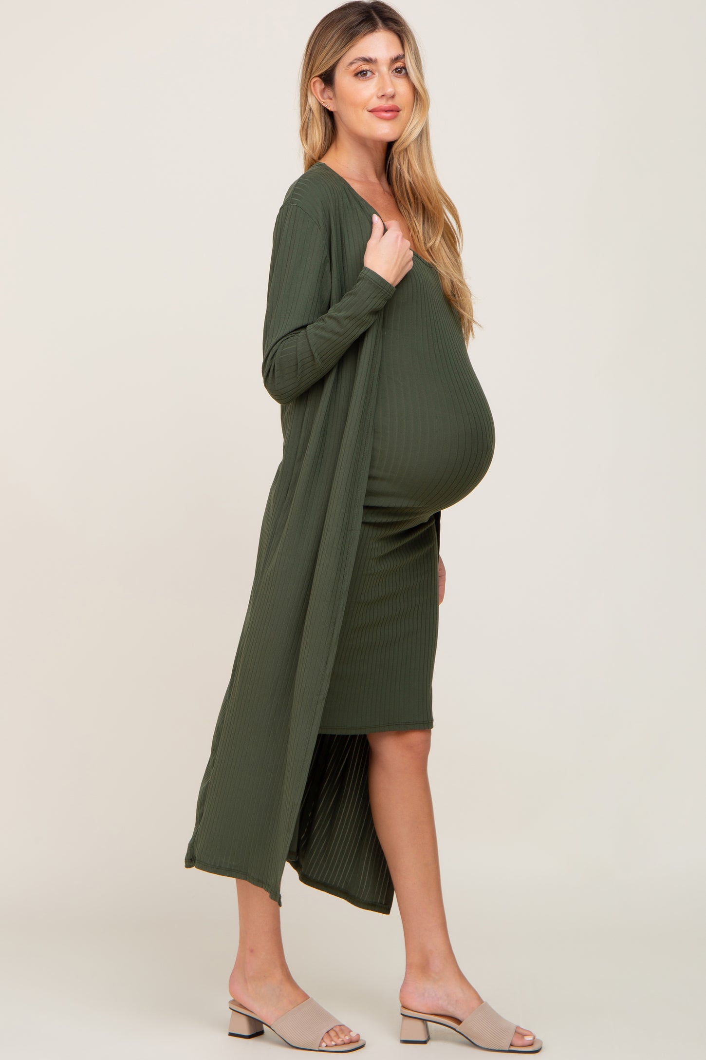 woman wearing a dark green maternity dress with a matching long cardigan and visible baby bump