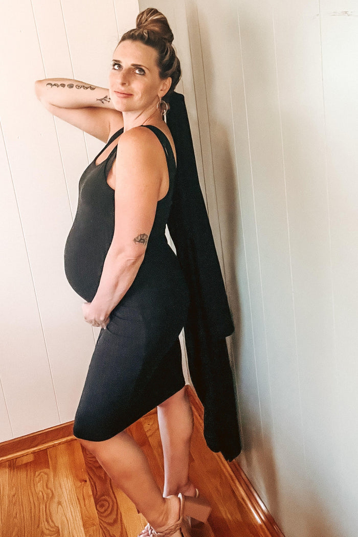 woman wearing a black maternity dress with a fitted silhouette and showing her baby bump