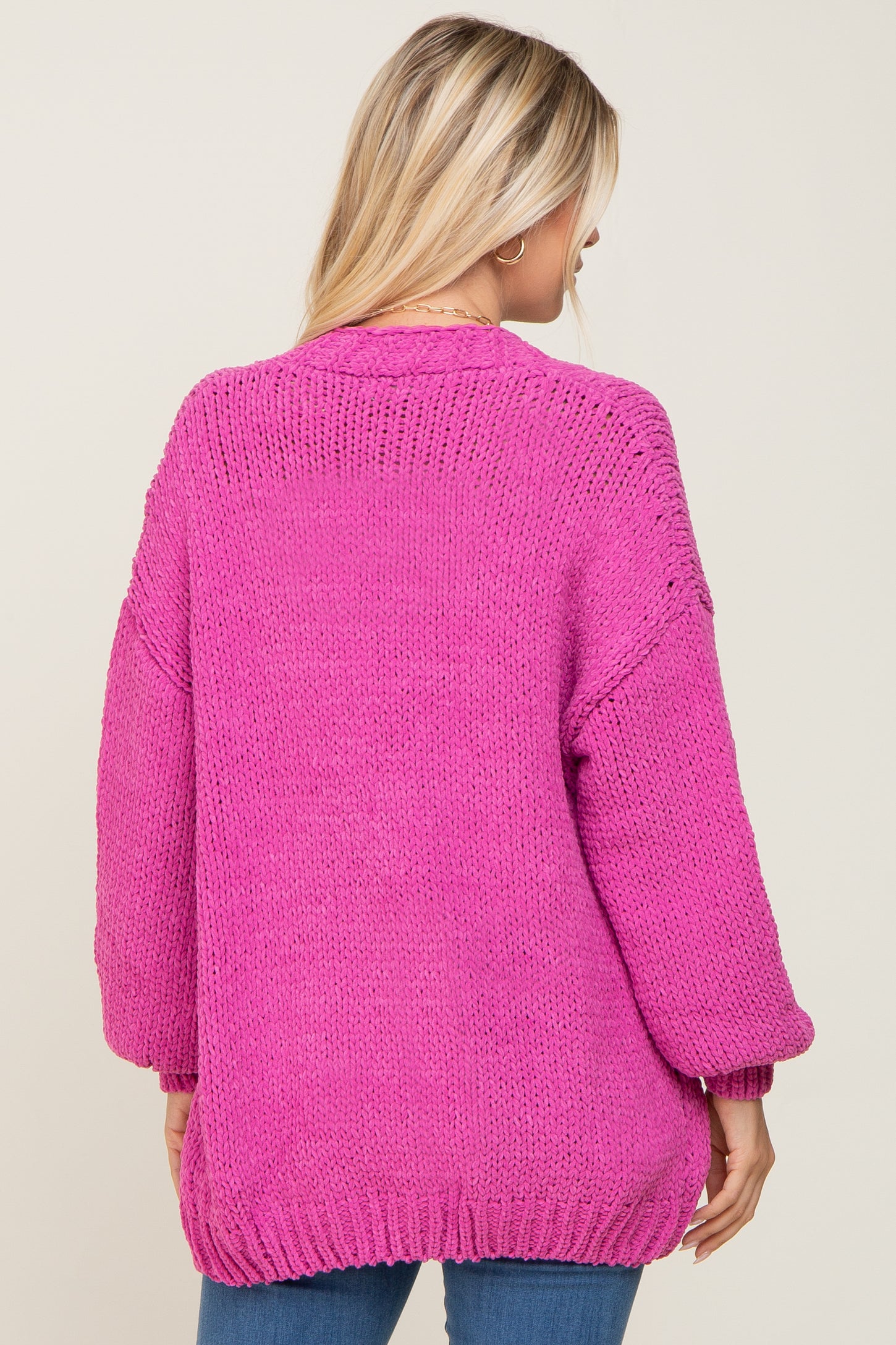 woman wearing a hot pink oversized knit sweater with balloon sleeves and a relaxed fit