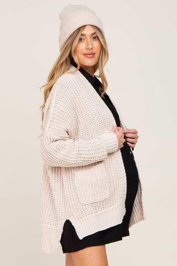 woman wearing a light pink maternity cardigan and matching beanie, with a visible baby bump