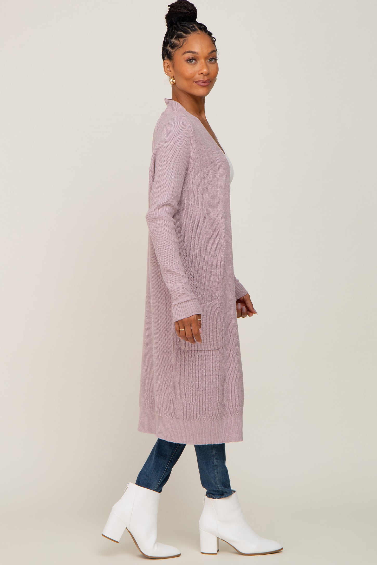 woman wearing a light purple long cardigan paired with blue jeans and white ankle boots
