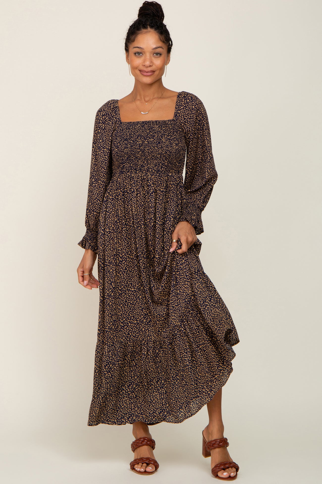 Woman wearing a navy blue and tan leopard print smocked maxi dress with long sleeves and brown braided heels