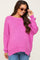 woman wearing a bright pink oversized maternity sweater with a wide neckline and long sleeves, smiling while adjusting her sunglasses