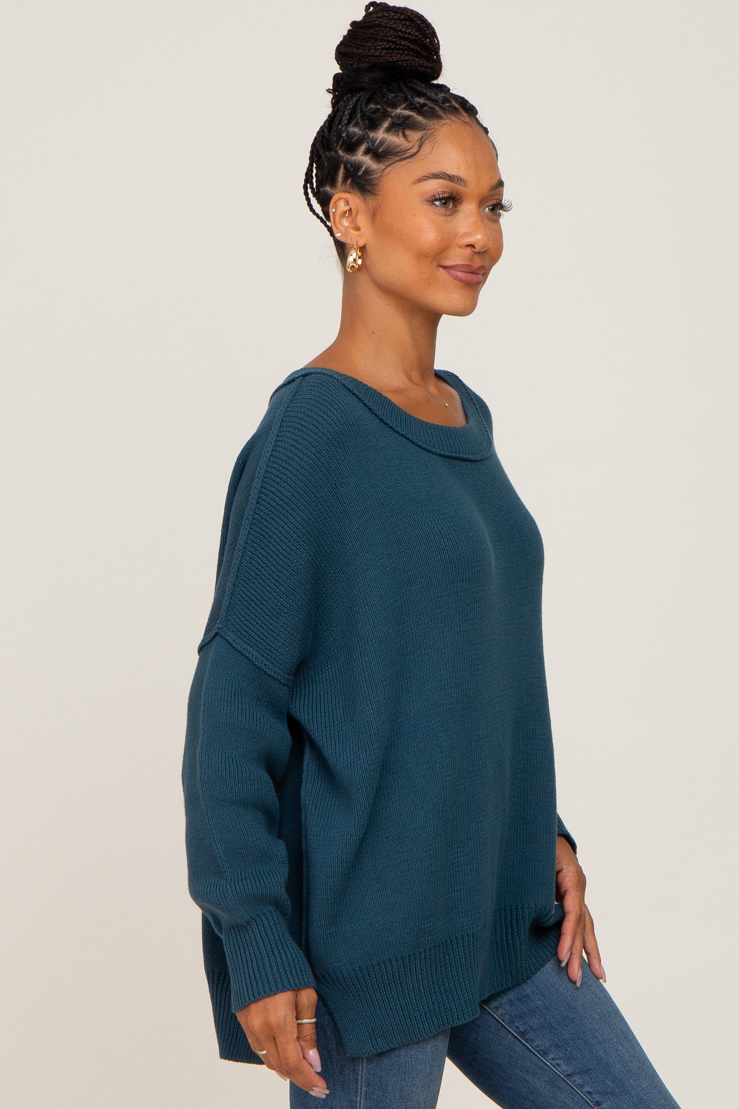 woman wearing a teal oversized sweater with a scoop neck and long sleeves, paired with blue jeans