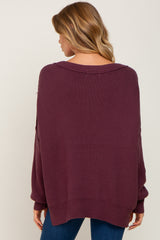 woman wearing a burgundy oversized knit sweater with a scoop neck and loose sleeves, seen from the back