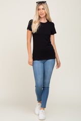 woman wearing a black short sleeve t-shirt and light blue skinny jeans with white sneakers and sunglasses on her head