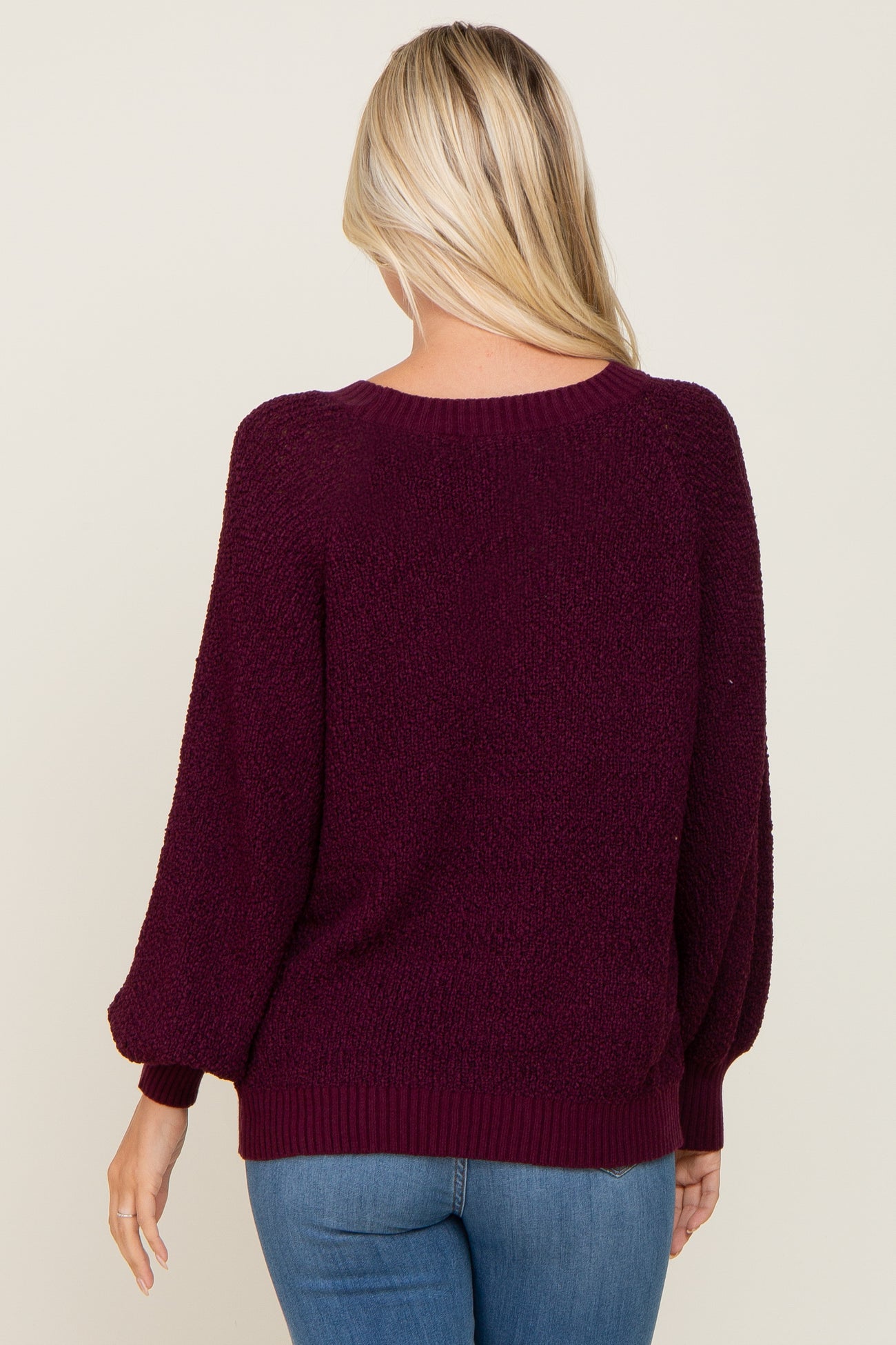 woman wearing a burgundy oversized sweater with balloon sleeves, viewed from the back