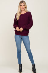 woman wearing a dark burgundy oversized knitted sweater with long sleeves and blue skinny jeans