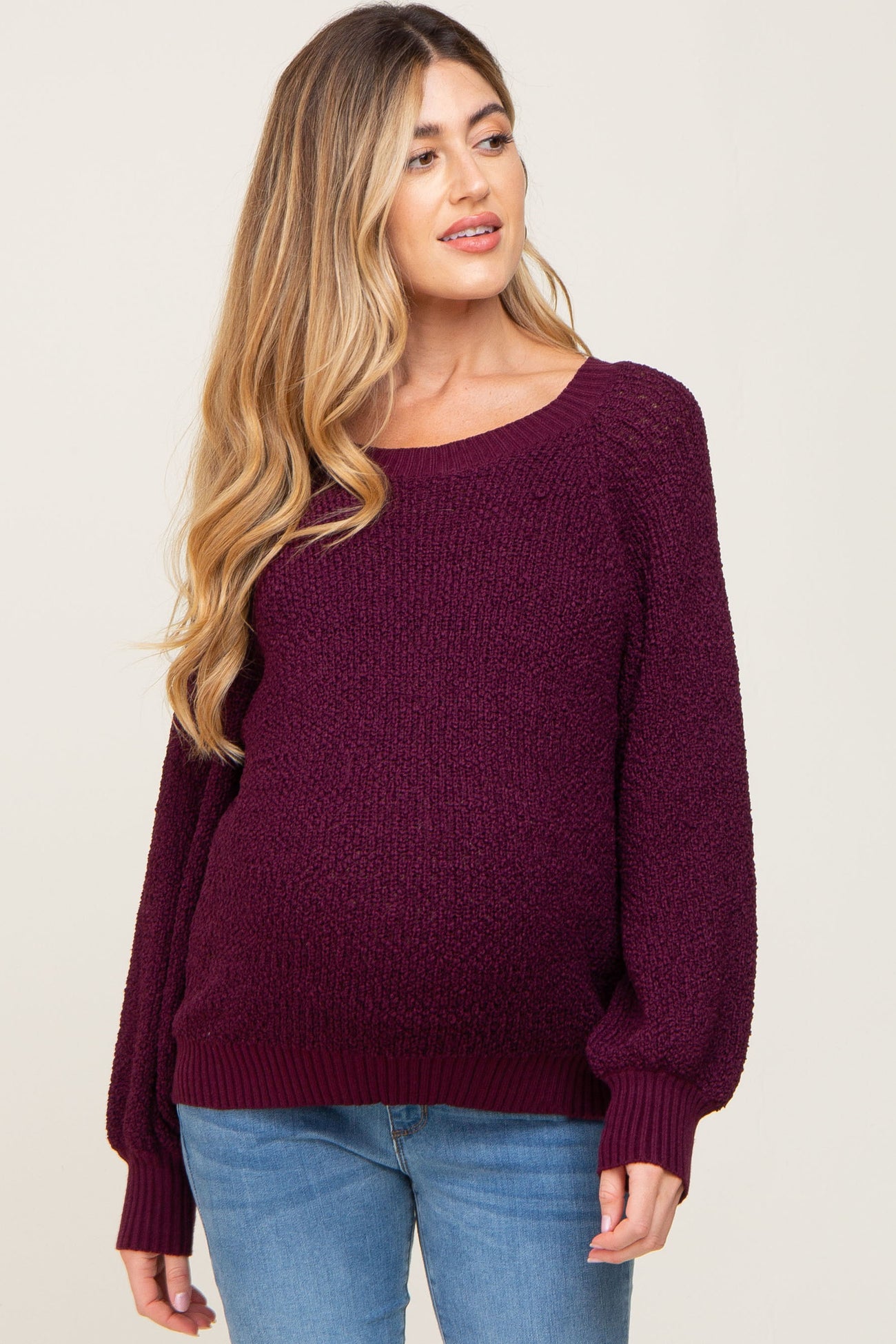 woman wearing a burgundy chunky knit maternity sweater with a relaxed fit and a visible baby bump