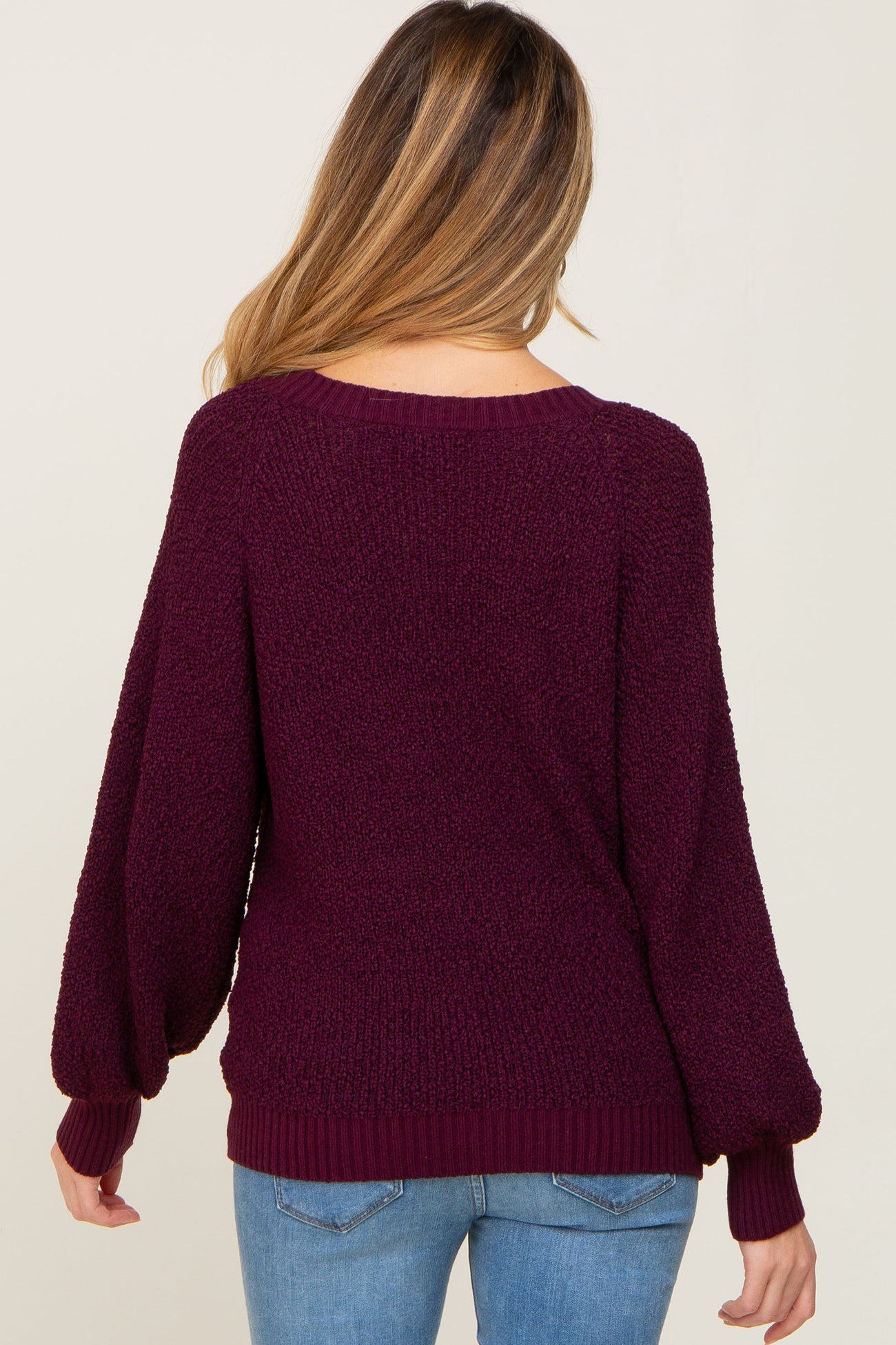 woman wearing a burgundy maternity sweater with balloon sleeves and a relaxed fit, viewed from the back