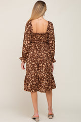 woman wearing a brown floral long sleeve maternity dress with a fitted bodice and ruffled hem