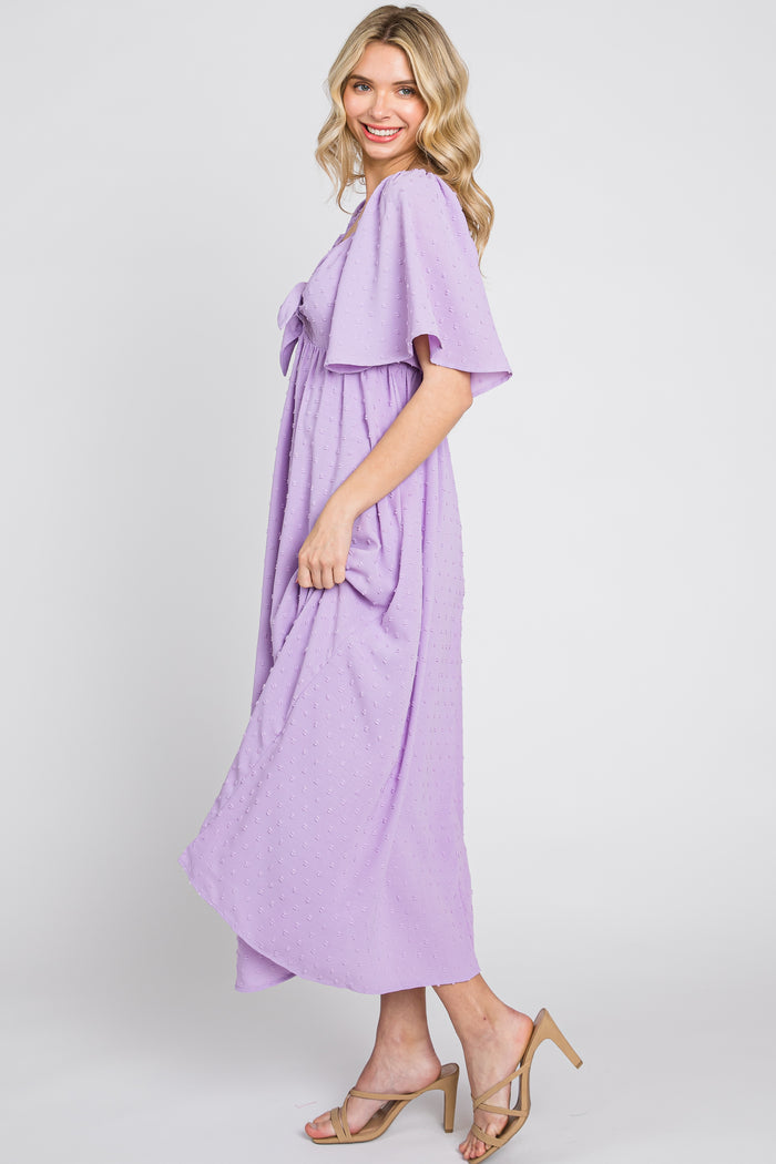 woman wearing a lavender short sleeve maxi dress with a bow detail and a flowing silhouette