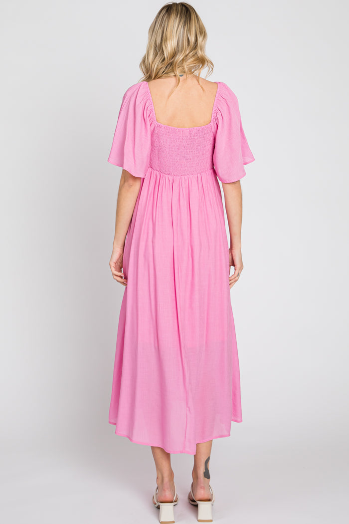 woman wearing a pink smocked back maxi dress with short flutter sleeves and a square neckline