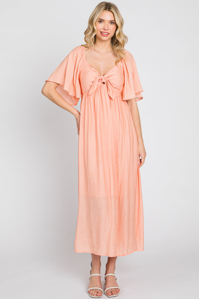woman wearing a peach maxi dress with flutter sleeves and a tie-front detail
