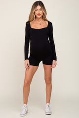 woman wearing a black long sleeve maternity romper and showing her baby bump