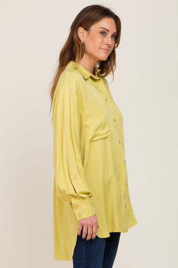 woman wearing a long sleeve yellow button down maternity shirt with a chest pocket and dark jeans
