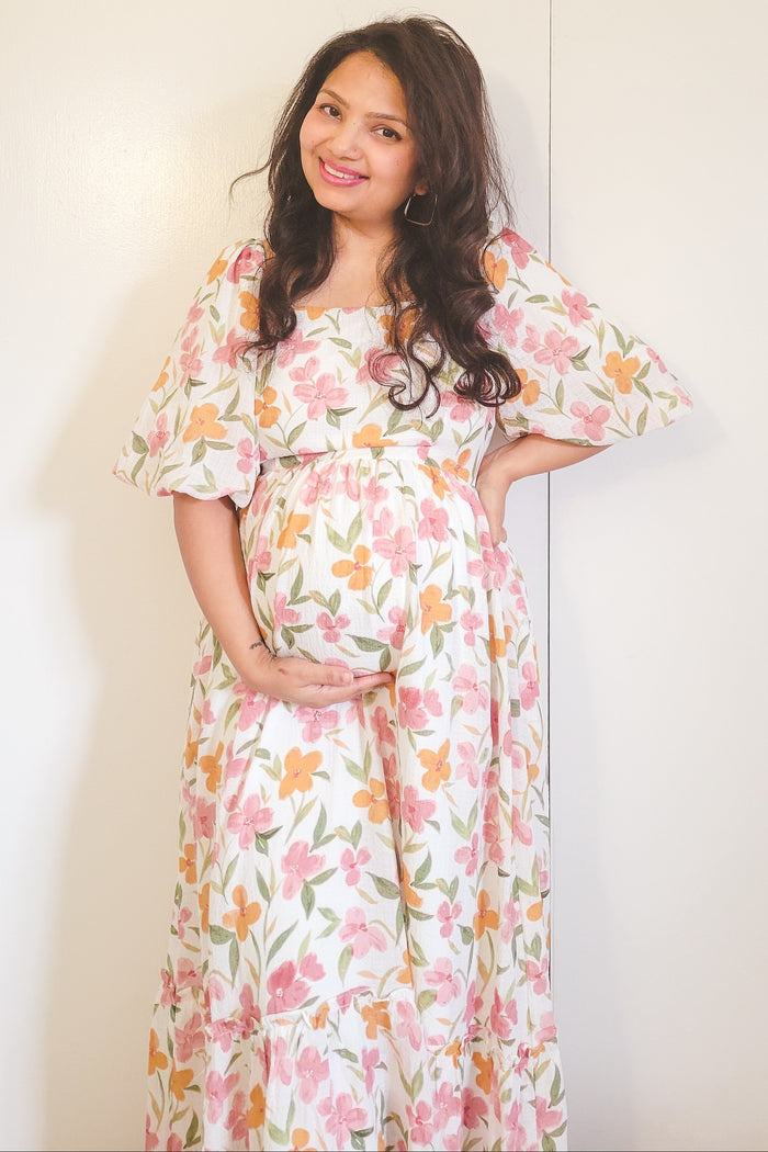 woman wearing a floral maternity maxi dress and holding her baby bump