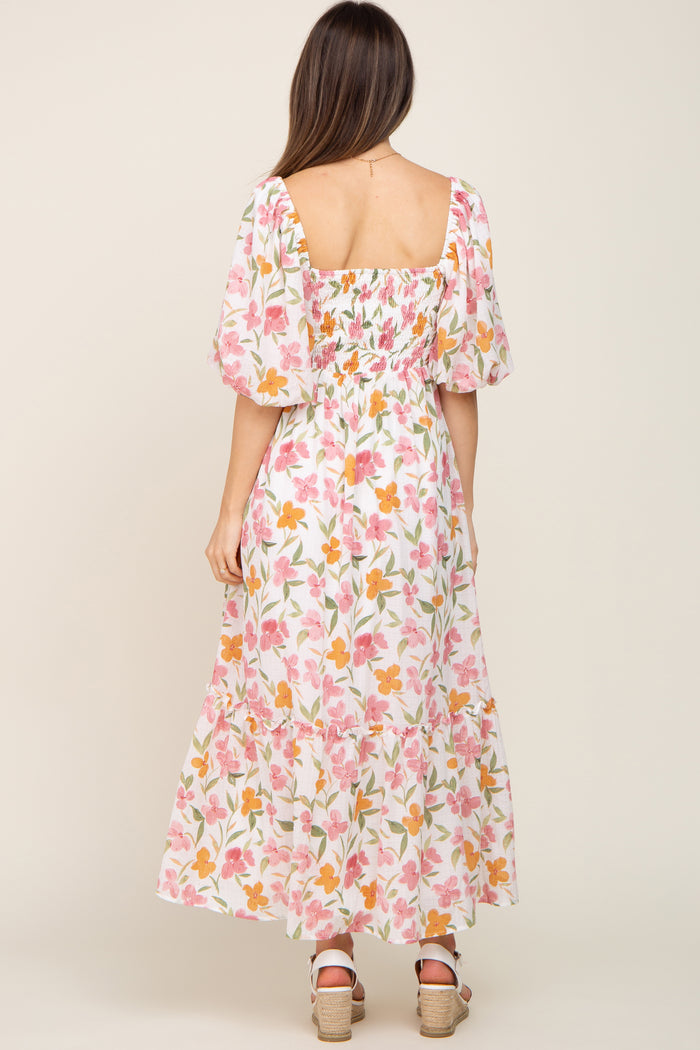 woman wearing a floral maternity maxi dress with puff sleeves and a smocked back, showcasing a baby bump