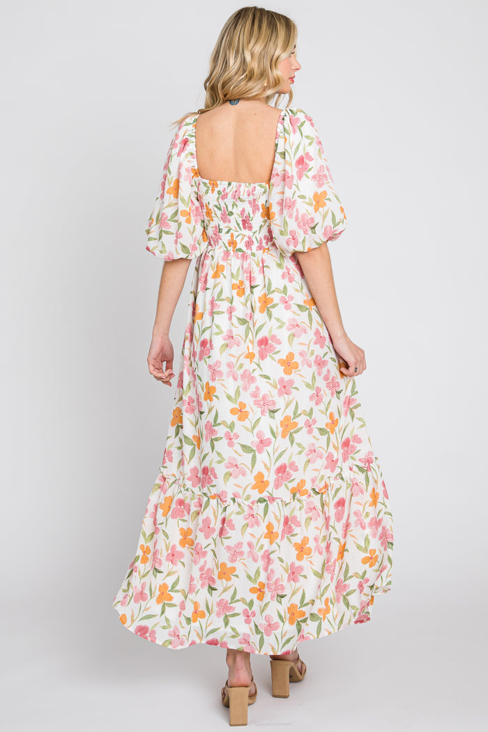 woman wearing a floral print maxi dress with puff sleeves and a square back, standing with her back to the camera